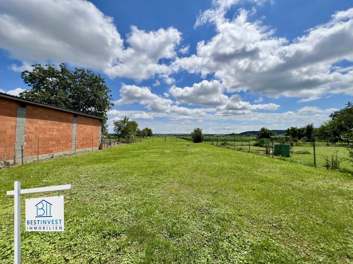 Weitläufige grüne Wiese mit Panoramablick auf die ländliche Umgebung und den Horizont.