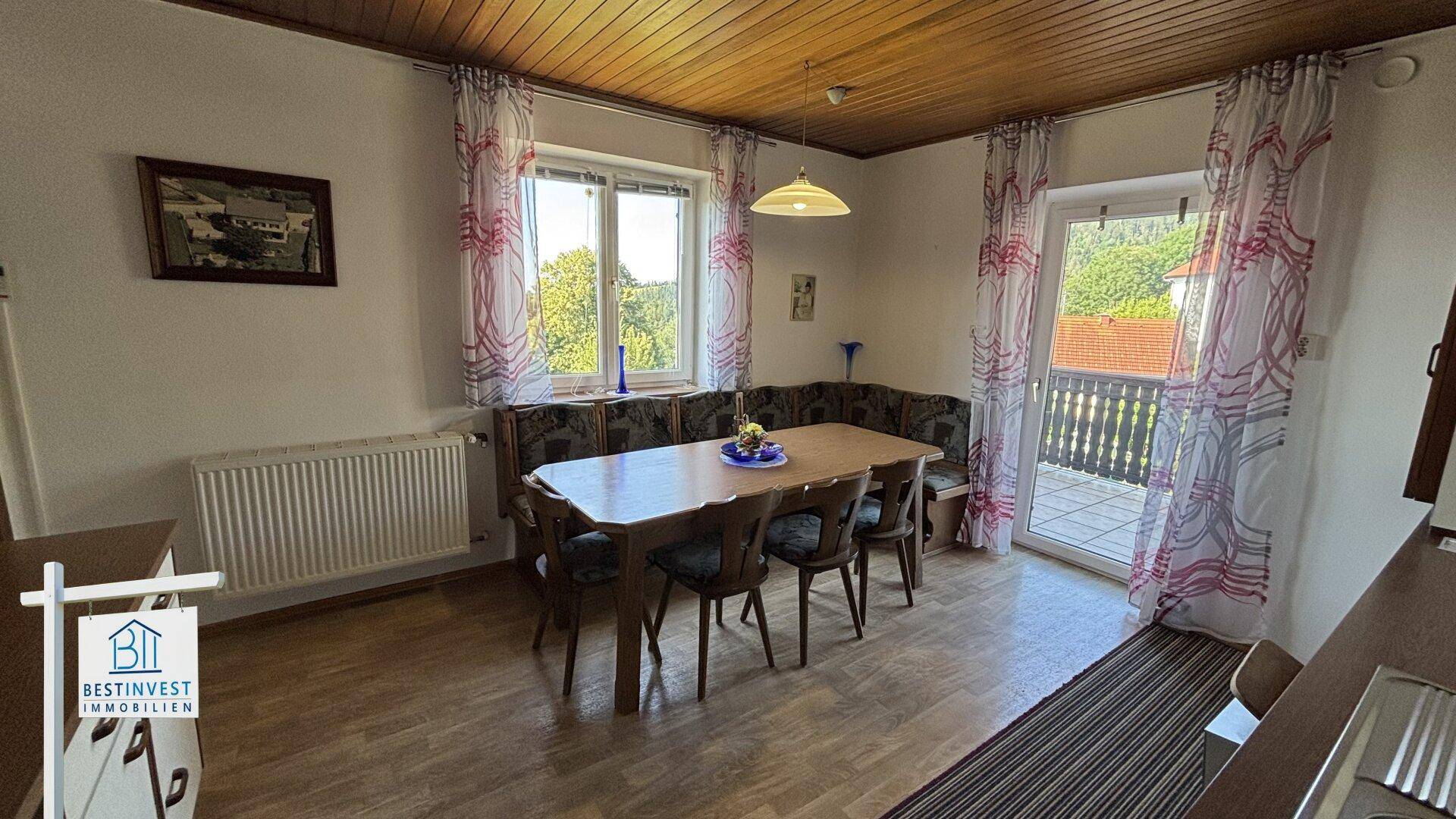 Heller Essbereich mit Holztisch, Eckbank und Zugang zu einem Balkon mit Bergblick.