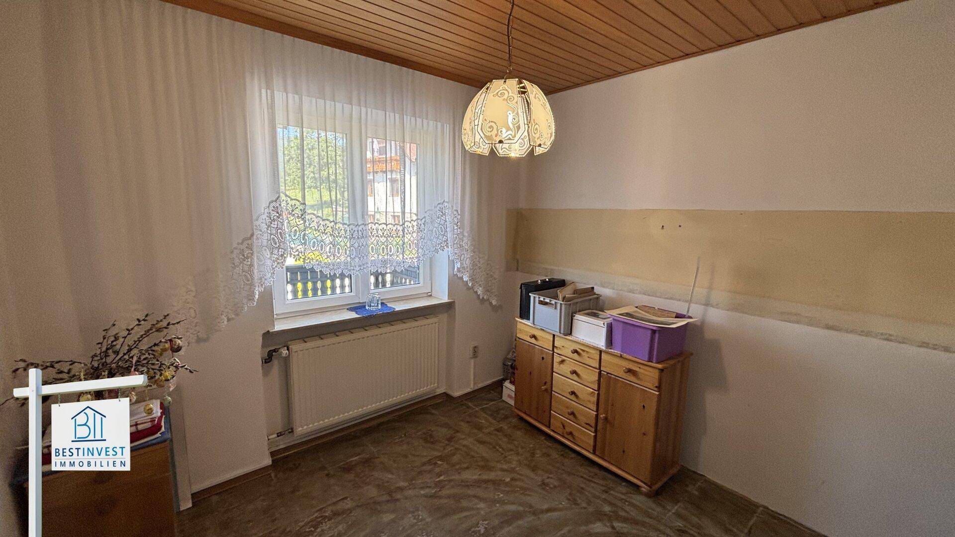 Raum mit Fenster, Heizkörper und einfacher Einrichtung, bereit zur Renovierung.