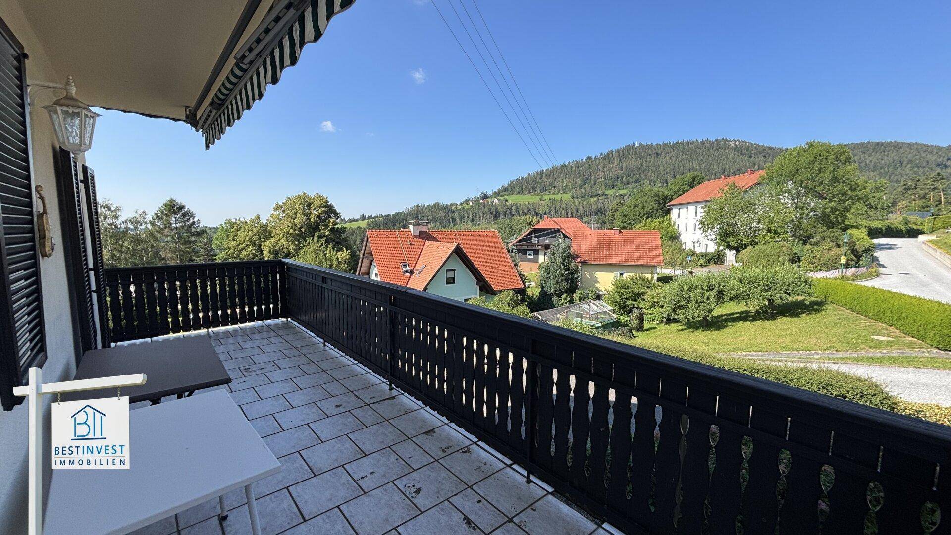 Geräumiger Balkon mit traditionellem Holzgeländer und Panoramablick auf die Natur.