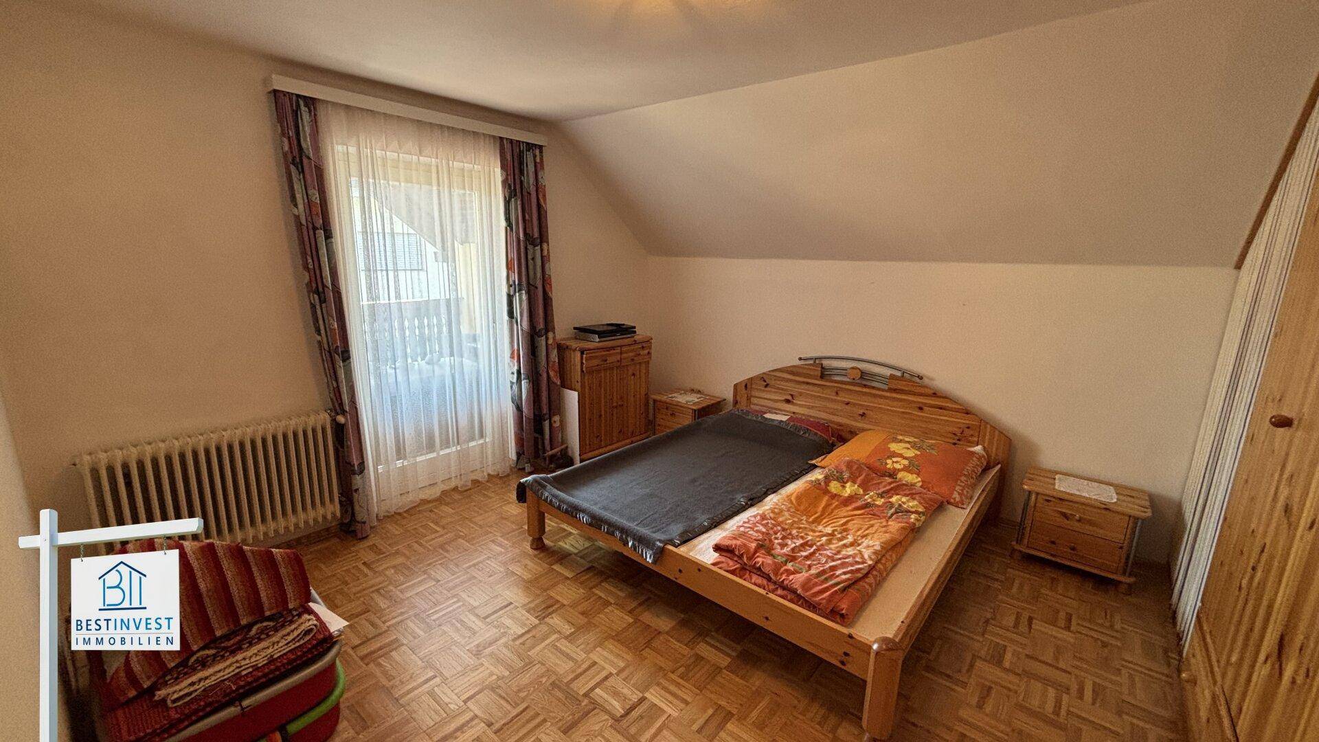 Schlafzimmer im Dachgeschoss mit Holzbett, Parkettboden und schrägen Decken.