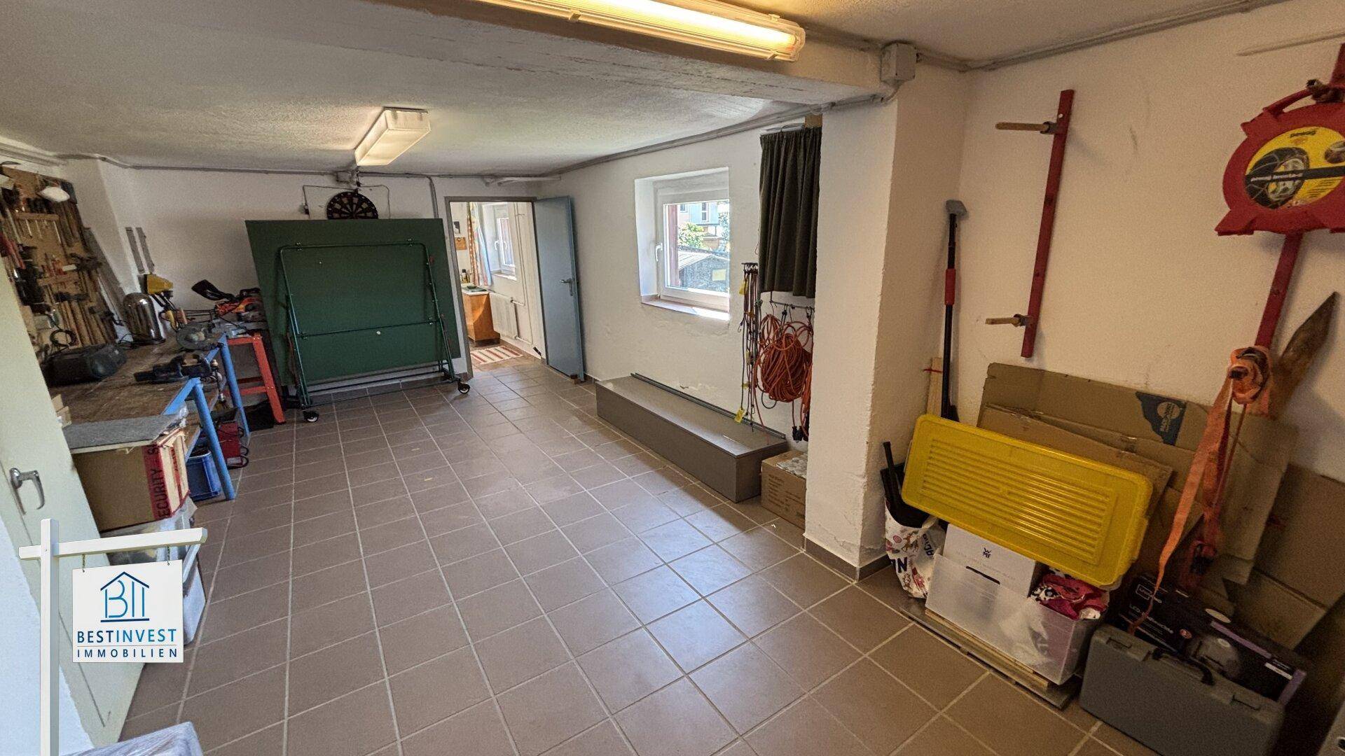 Großer Kellerraum mit Fliesenboden, Werkbank und Fenster, ideal als Hobbyraum.