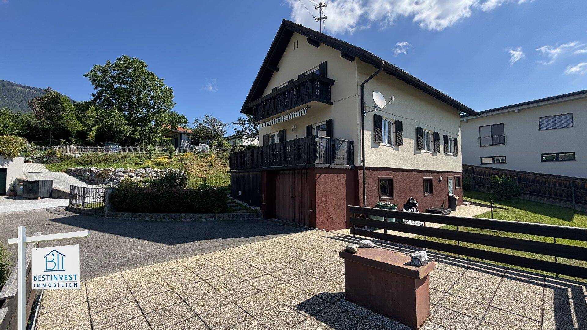 Große gepflasterte Terrasse an der Rückseite des Hauses mit Balkonen im Obergeschoss.