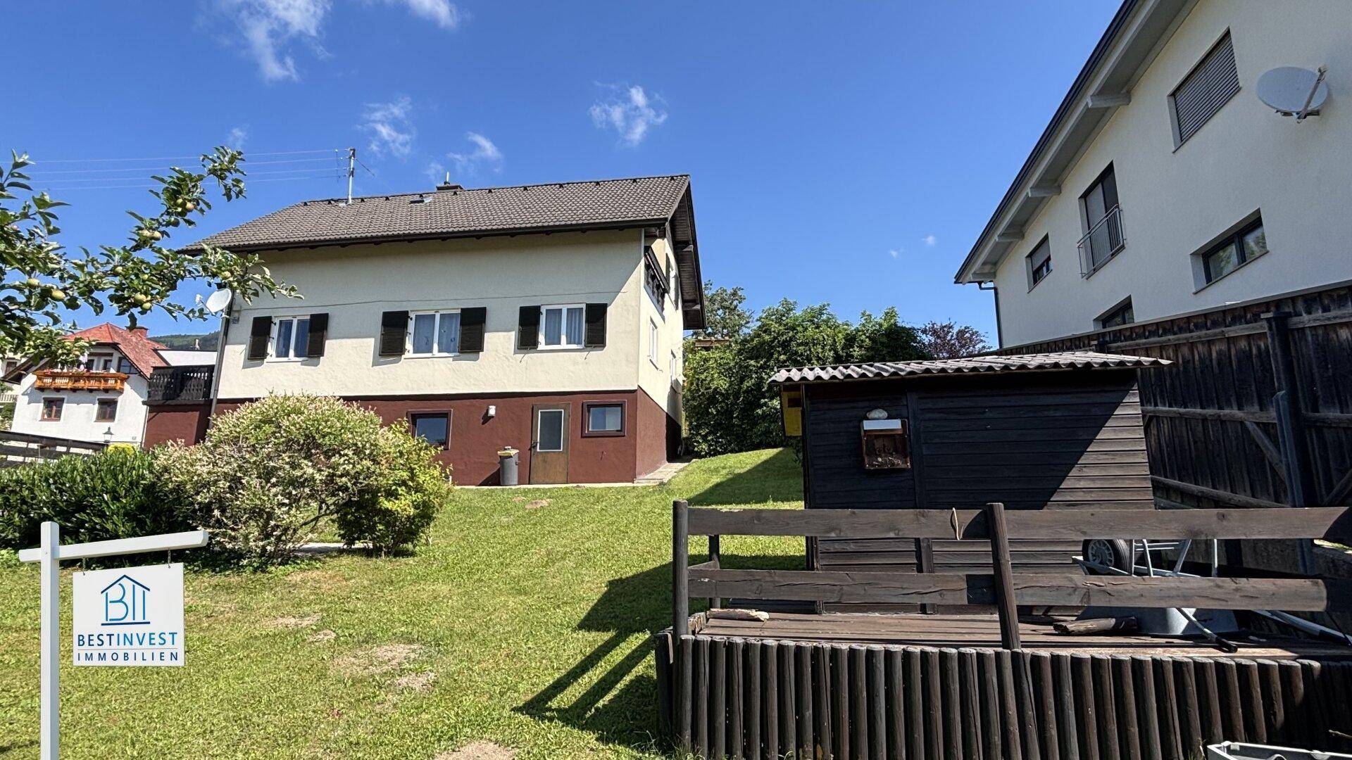 Seitenansicht des Hauses mit großem Gartenbereich und einem kleinen Gartenhaus.