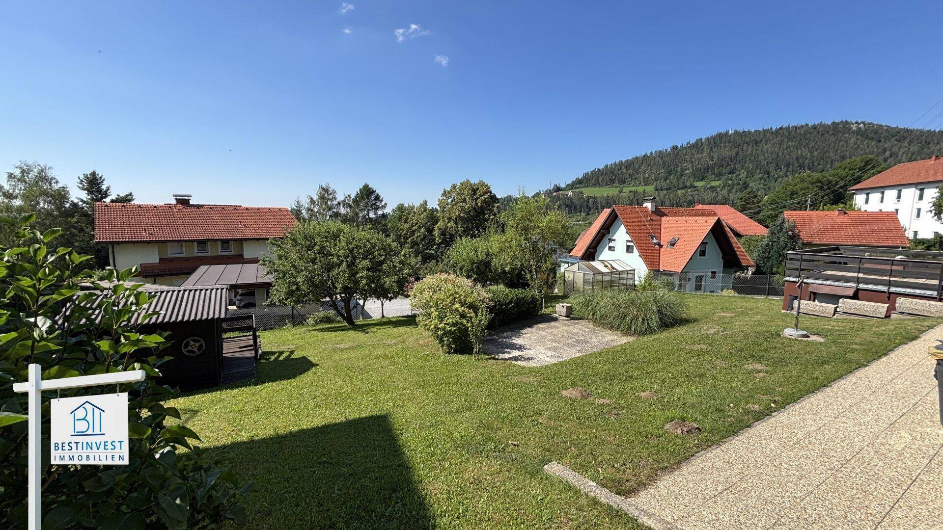 Großer Gartenbereich mit Rasenfläche, Bäumen und einem kleinen Gartenhaus.
