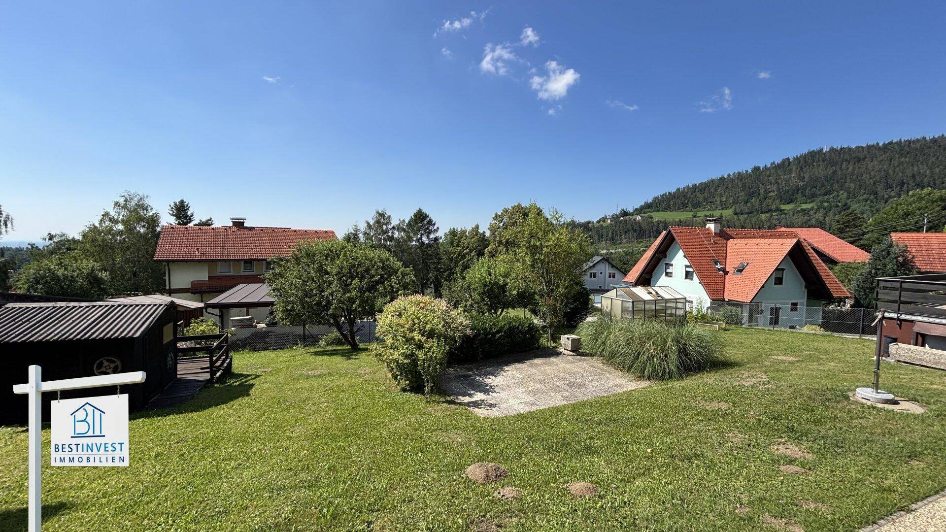 Weitläufiger Gartenbereich mit Rasenfläche, Bäumen und Blick auf die umliegende Landschaft.
