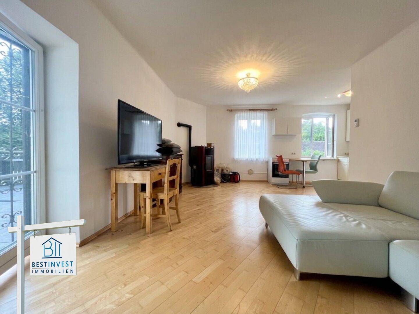 Offener Wohn- und Essbereich mit Sofa, Holzofen und Holzdielenboden.