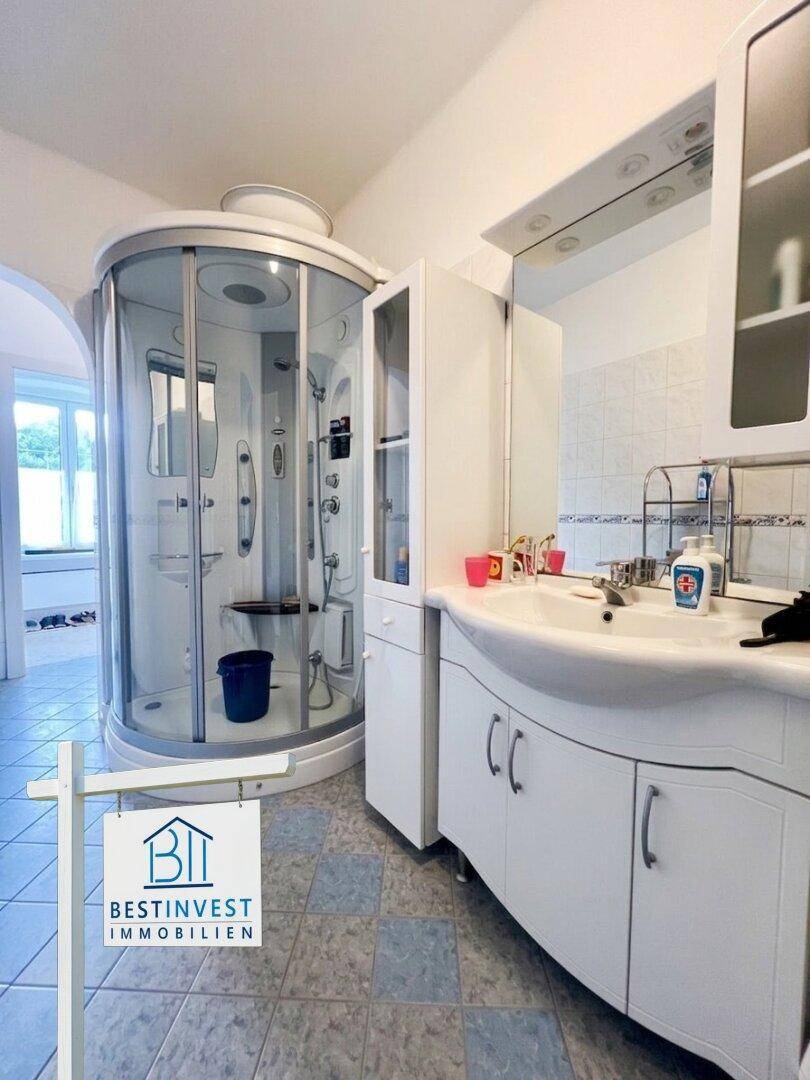 Badezimmer mit moderner Duschkabine, Waschbecken und Spiegelschrank.