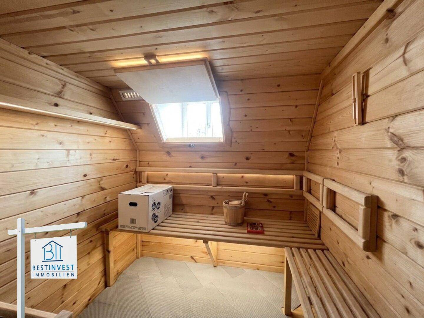 Gemütliche Sauna mit Holzverkleidung, Sitzbänken und einem Dachfenster für natürliches Licht.