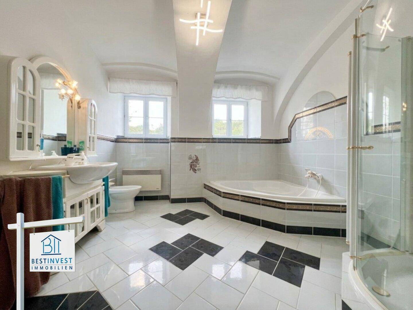 Großes Badezimmer mit Eckbadewanne, Duschkabine, Waschbecken und dekorativen Fliesen.