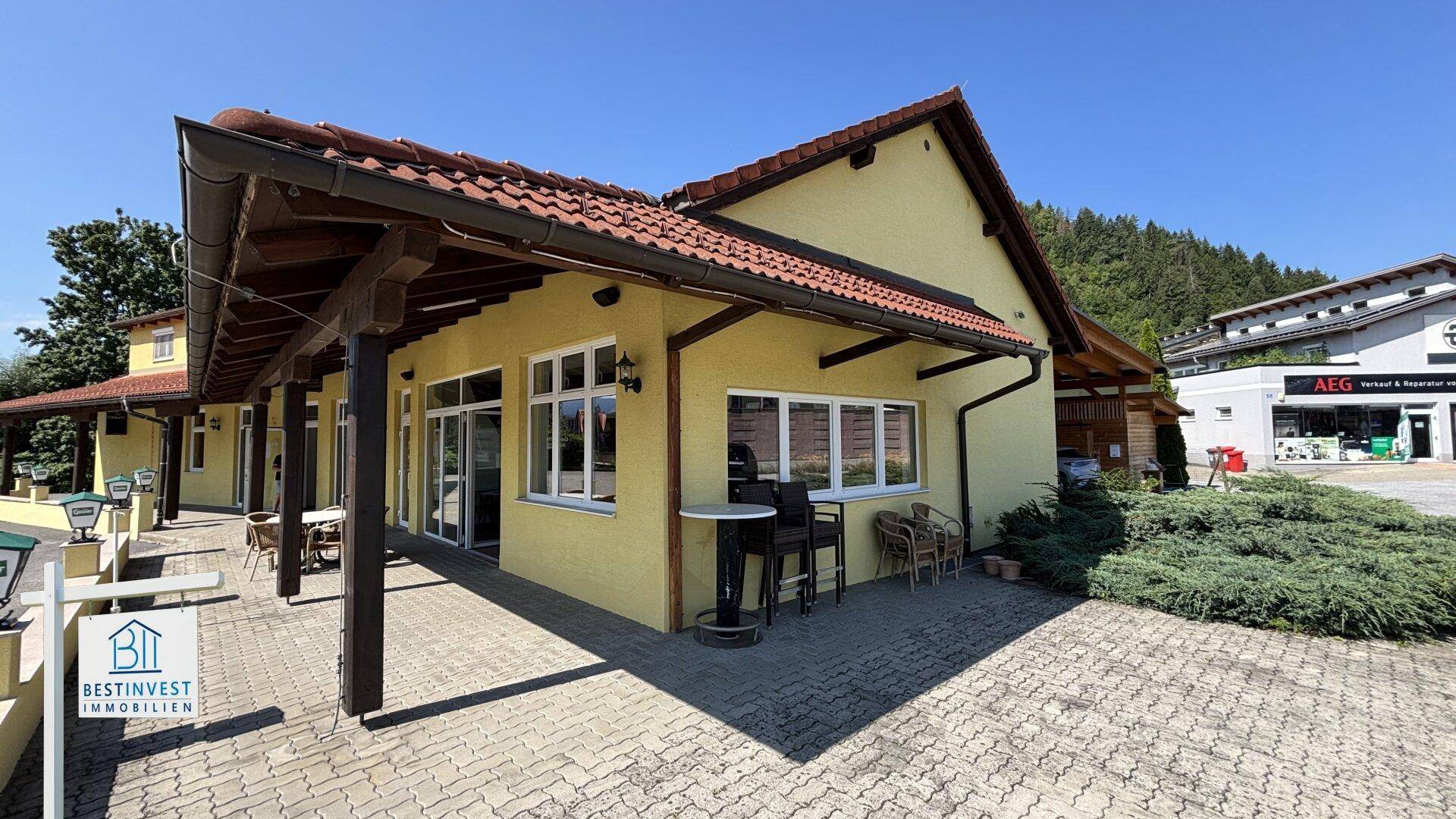 Außenbereich des Anwesens mit gepflasterter Fläche und Blick auf den Carport.