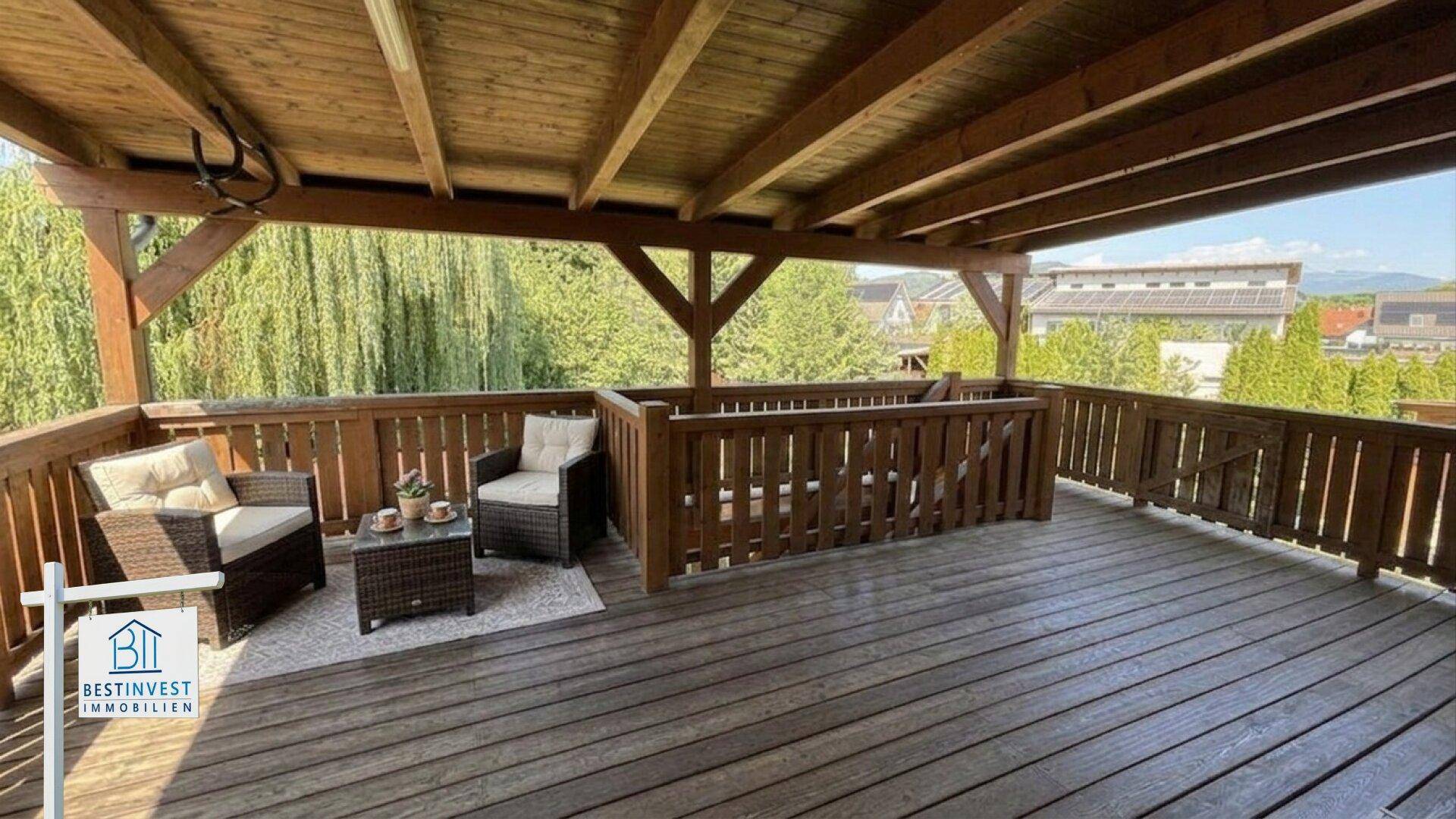 Geräumiger Holzbalkon mit bequemen Loungemöbeln und weitem Ausblick ins Grüne.
