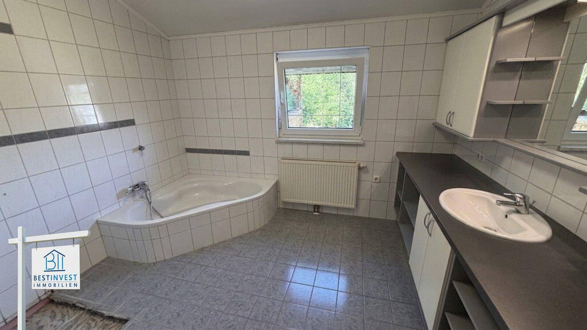 Badezimmer mit Eckbadewanne, Einzelwaschbecken und gefliesten Wänden und Boden.