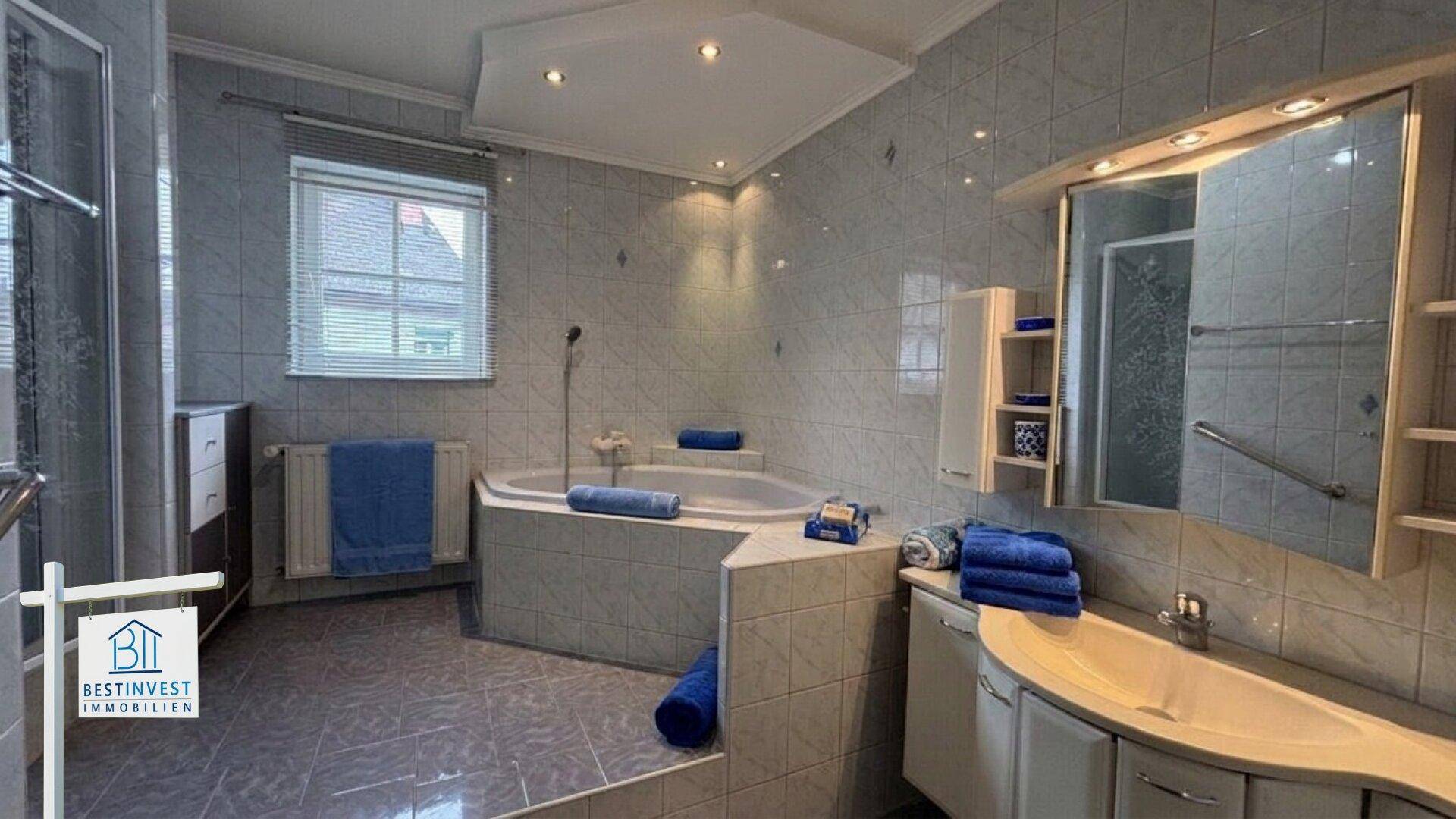 Gefliestes Badezimmer mit Eckbadewanne, Dusche und Spiegelschrank.