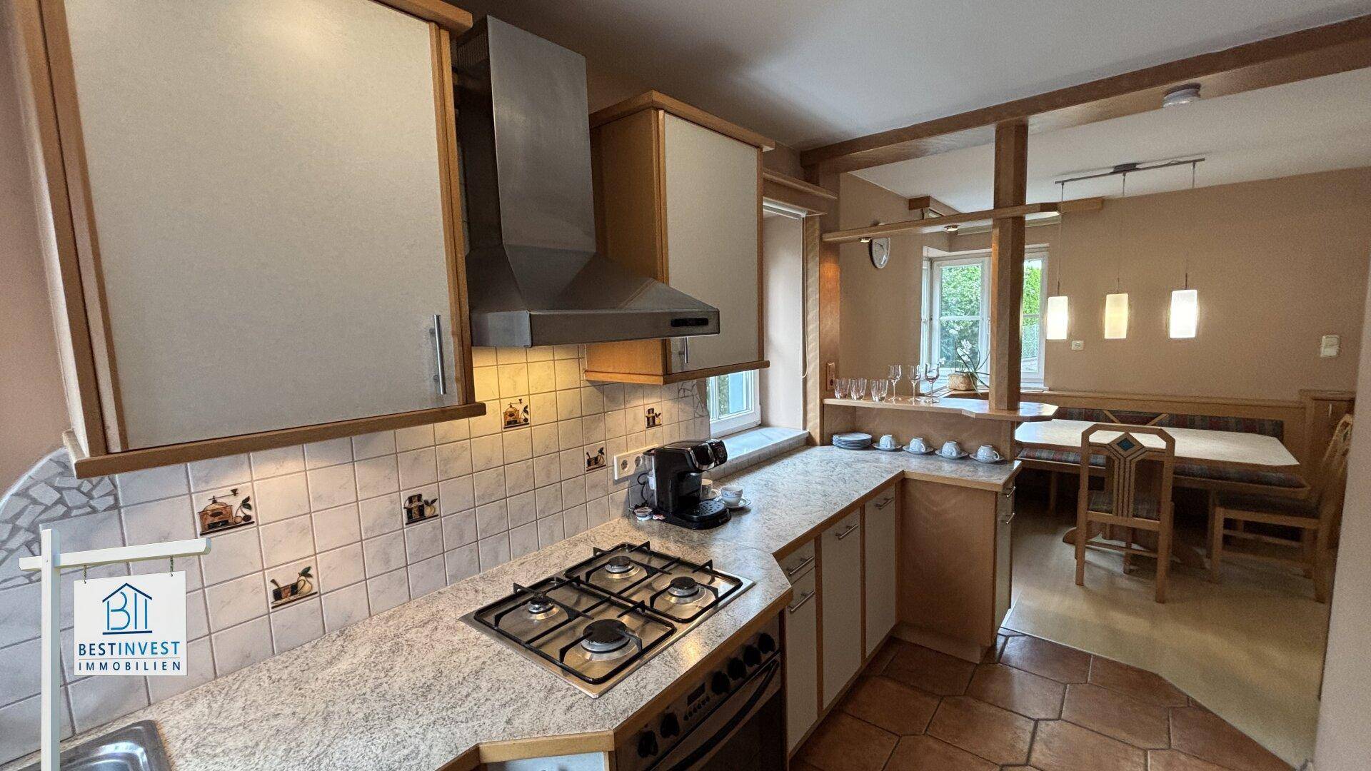 Traditionelle Küche mit Gasherd, Fliesenboden und Essbereich im Hintergrund.