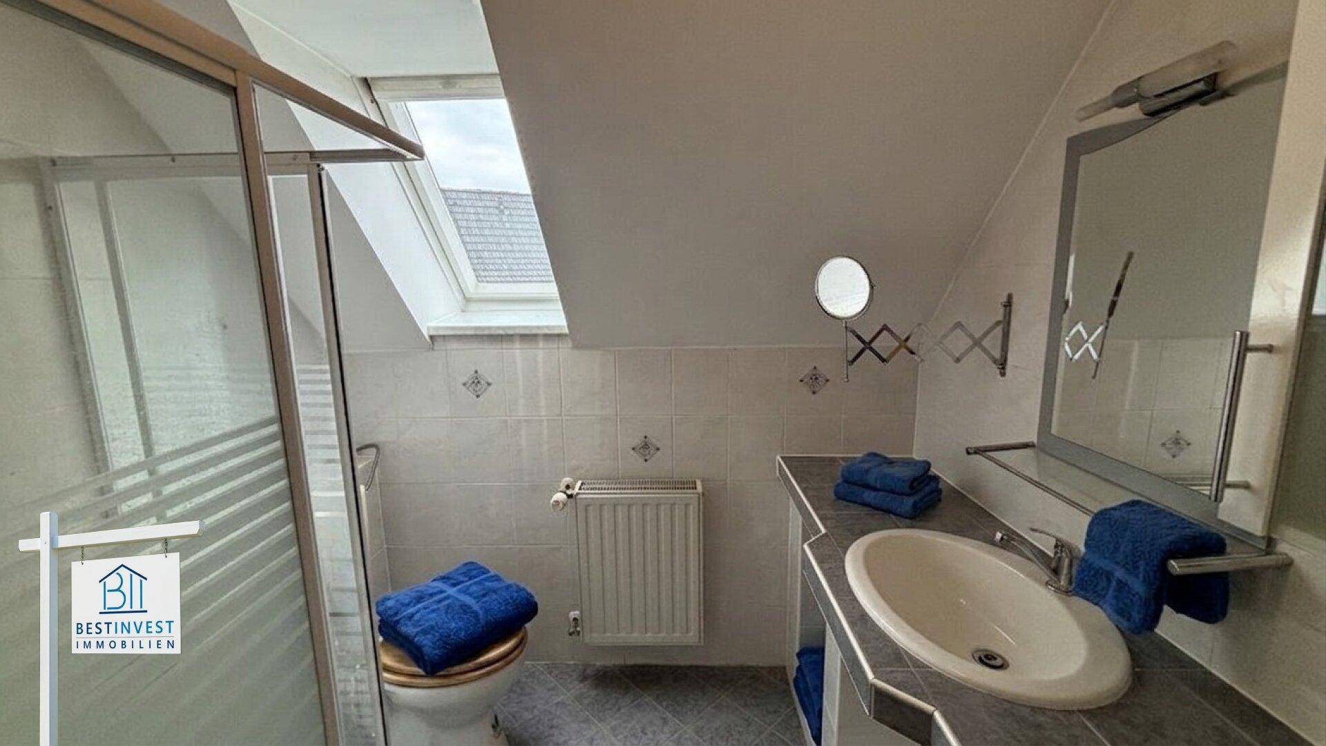 Badezimmer im Dachgeschoss mit Dusche, Dachfenster und Waschtisch.