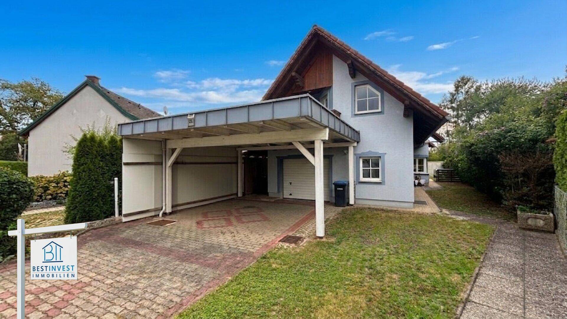 Freistehendes Haus mit Carport, Garage und gepflasterter Einfahrt.