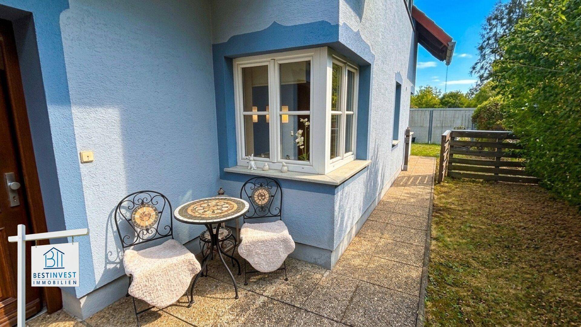 Kleiner Sitzbereich vor dem Haus mit Tisch und Stühlen.