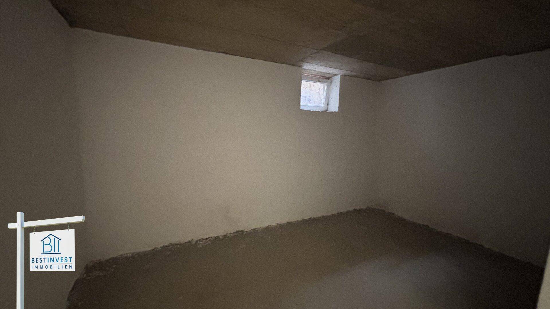 Unfertiger Kellerraum mit kleinem Fenster und rohem Betonboden, bereit für Ausbau.