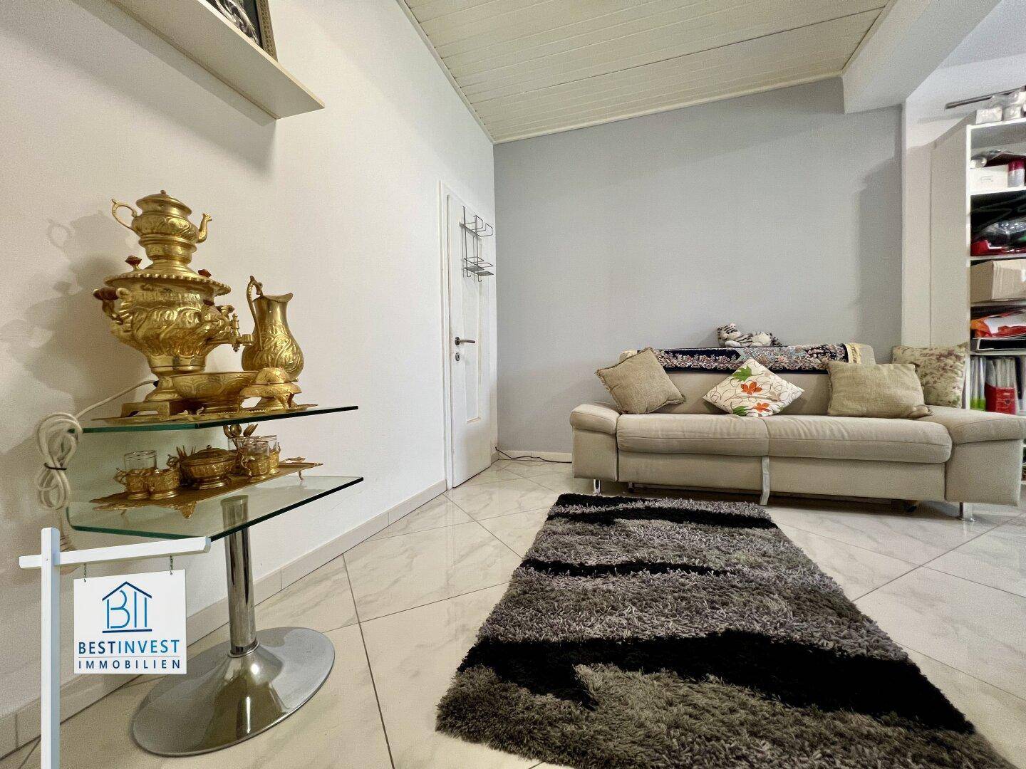 Kleiner, heller Raum mit Sofa und Teppich, möglicherweise ein Gästezimmer oder eine Nische.