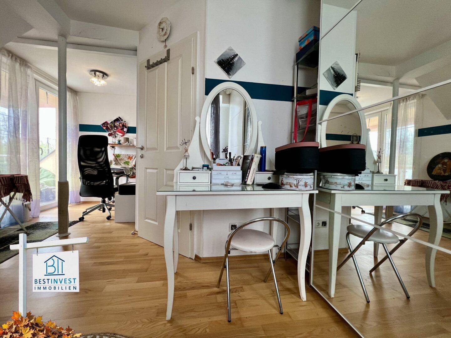 Heller offener Bereich mit Holzboden und Schminktisch, vielseitig nutzbar.