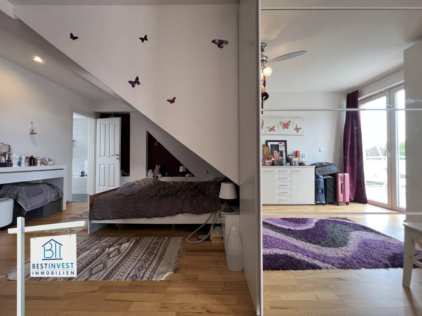Gemütliches Schlafzimmer mit Dachschräge, Holzboden und Zugang zum Balkon.