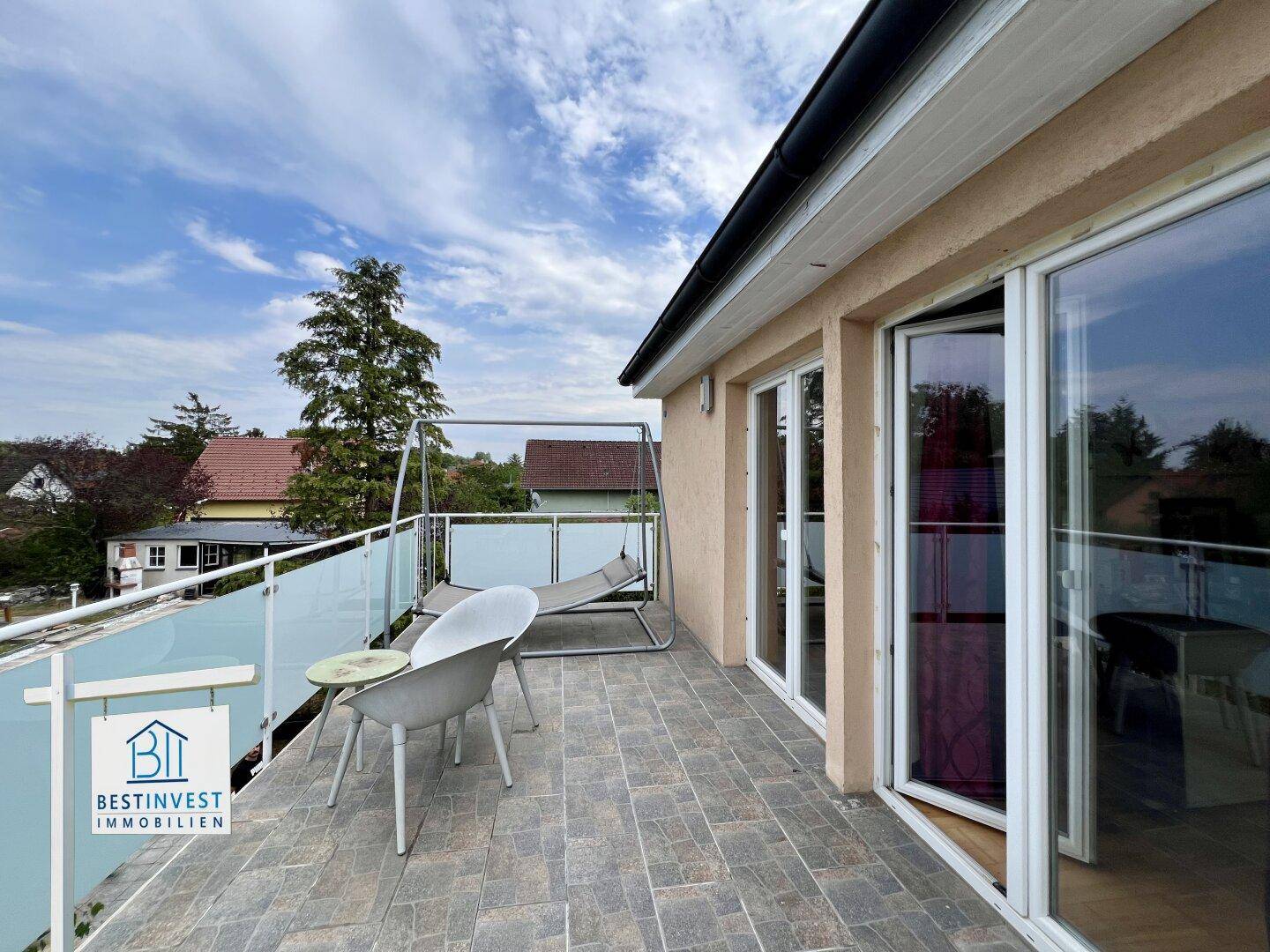 Geräumiger Balkon mit Fliesenboden, Schaukel und Blick ins Grüne.