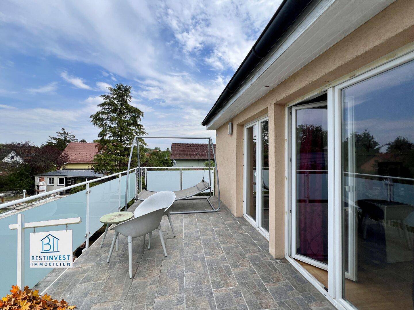 Geräumiger Balkon mit Fliesenboden, Schaukel und Sitzgelegenheiten, bietet viel Platz im Freien.