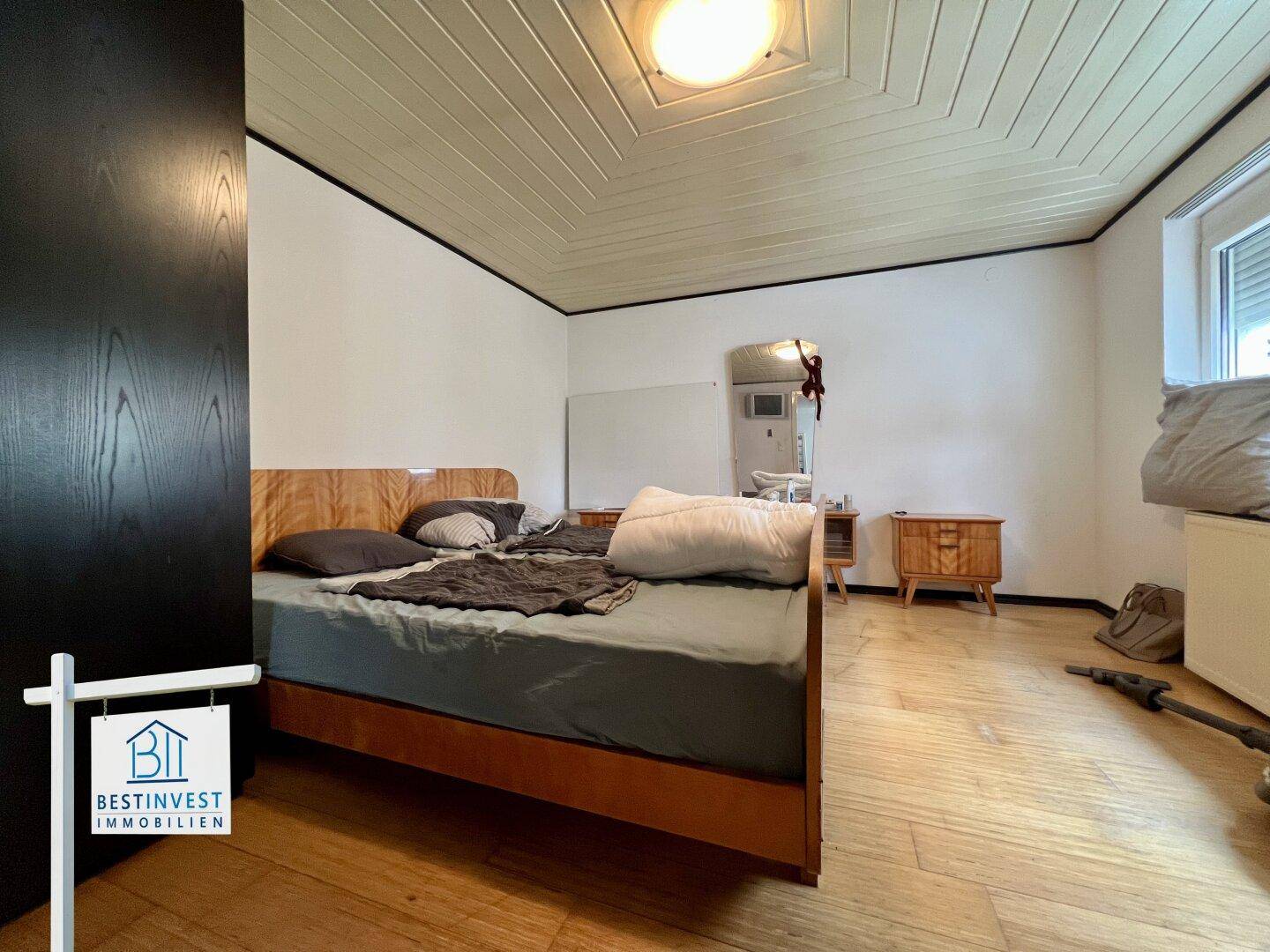Schlafzimmer mit Holzbettrahmen, Holzboden und einer Decke mit Holzpaneelen.