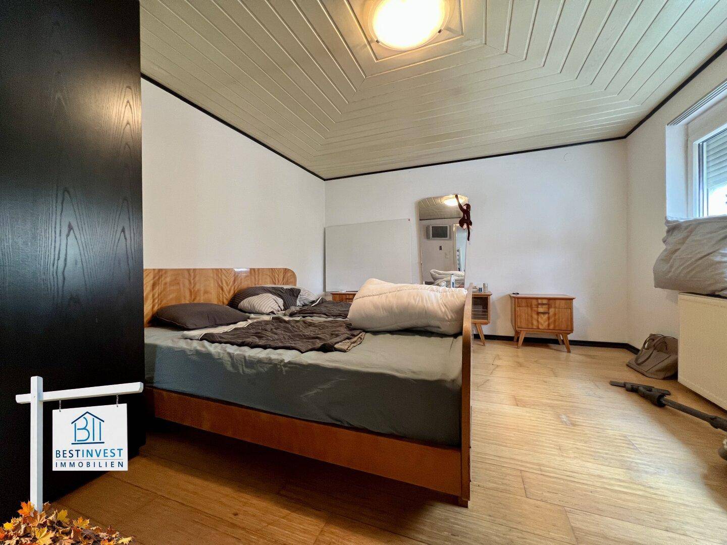 Schlafzimmer mit Holzbett, Holzboden und einer charakteristischen Holzdecke, die Gemütlichkeit ausstrahlt.