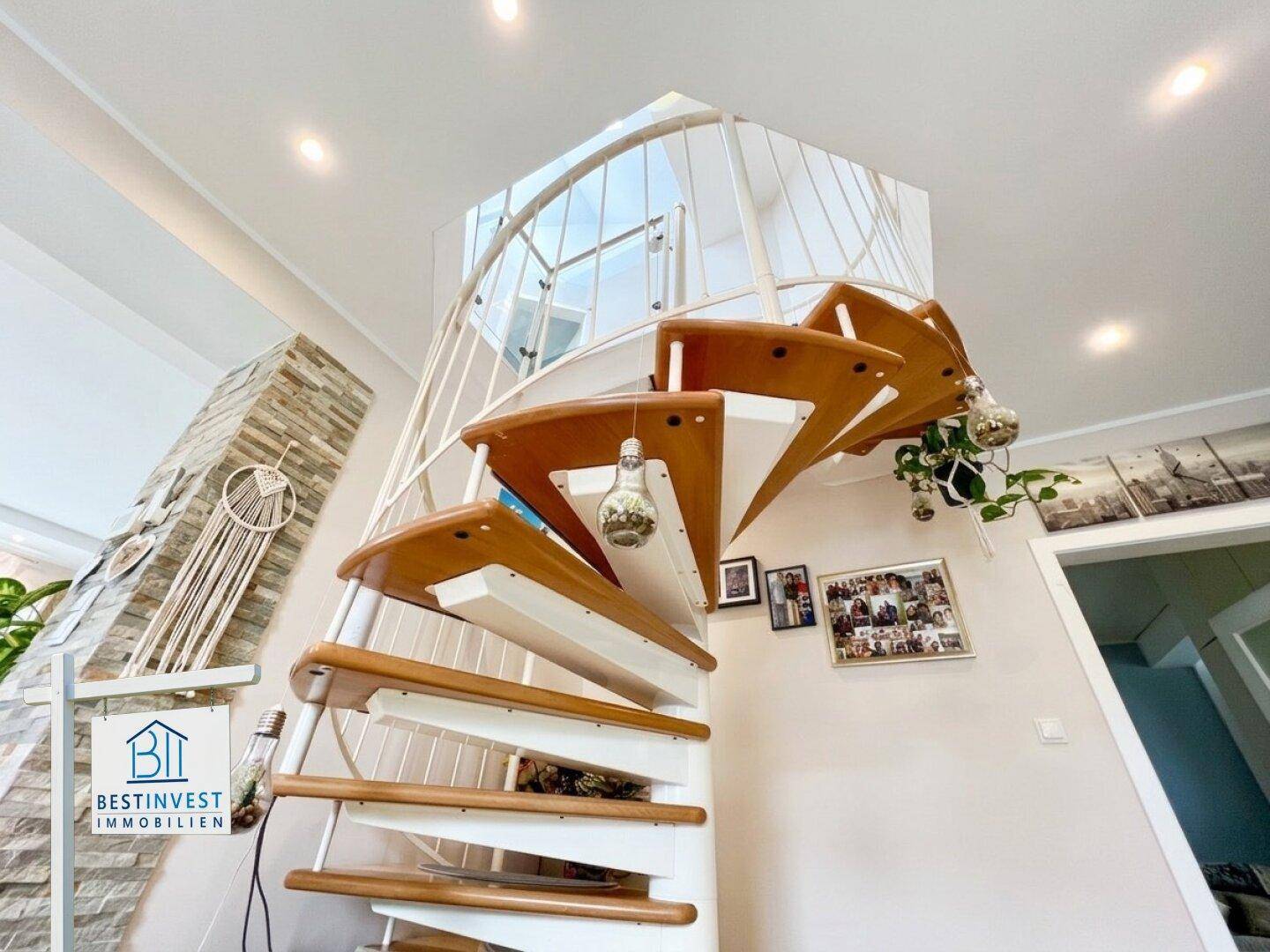 Elegante Wendeltreppe mit Holzstufen und Metallgeländer, die die Etagen verbindet.