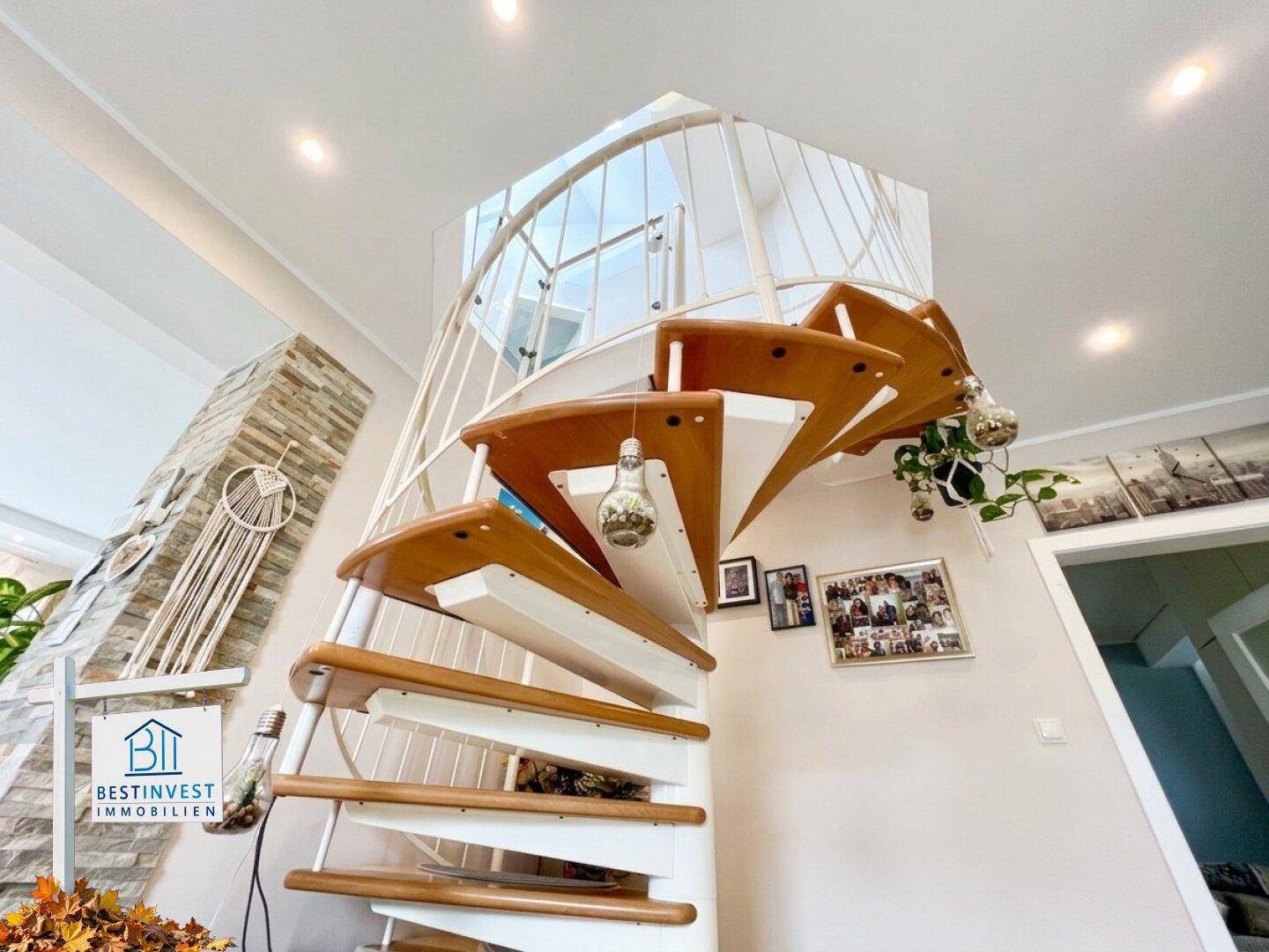 Elegante Wendeltreppe mit Holzstufen und modernem Geländer, verbindet die Etagen.