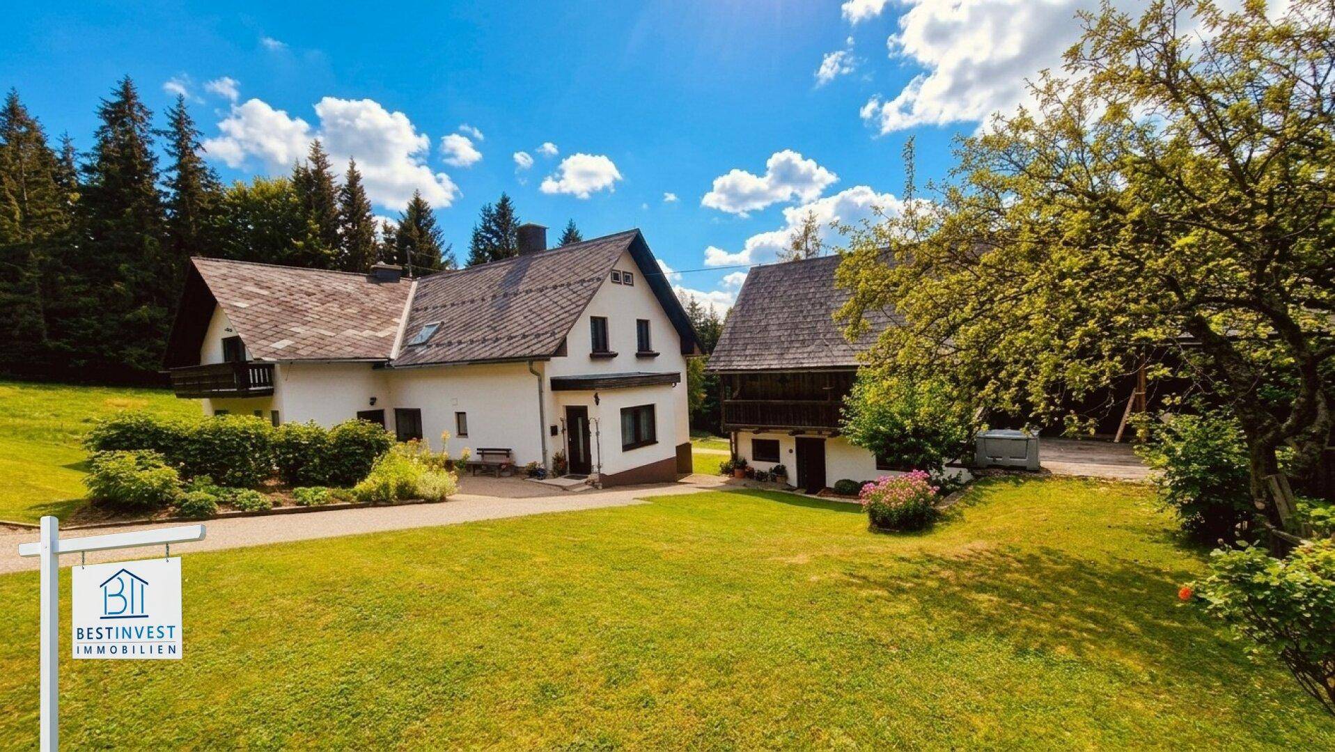 Idyllisches Anwesen mit Haupthaus und Scheune, umgeben von grünen Wiesen und Bäumen.