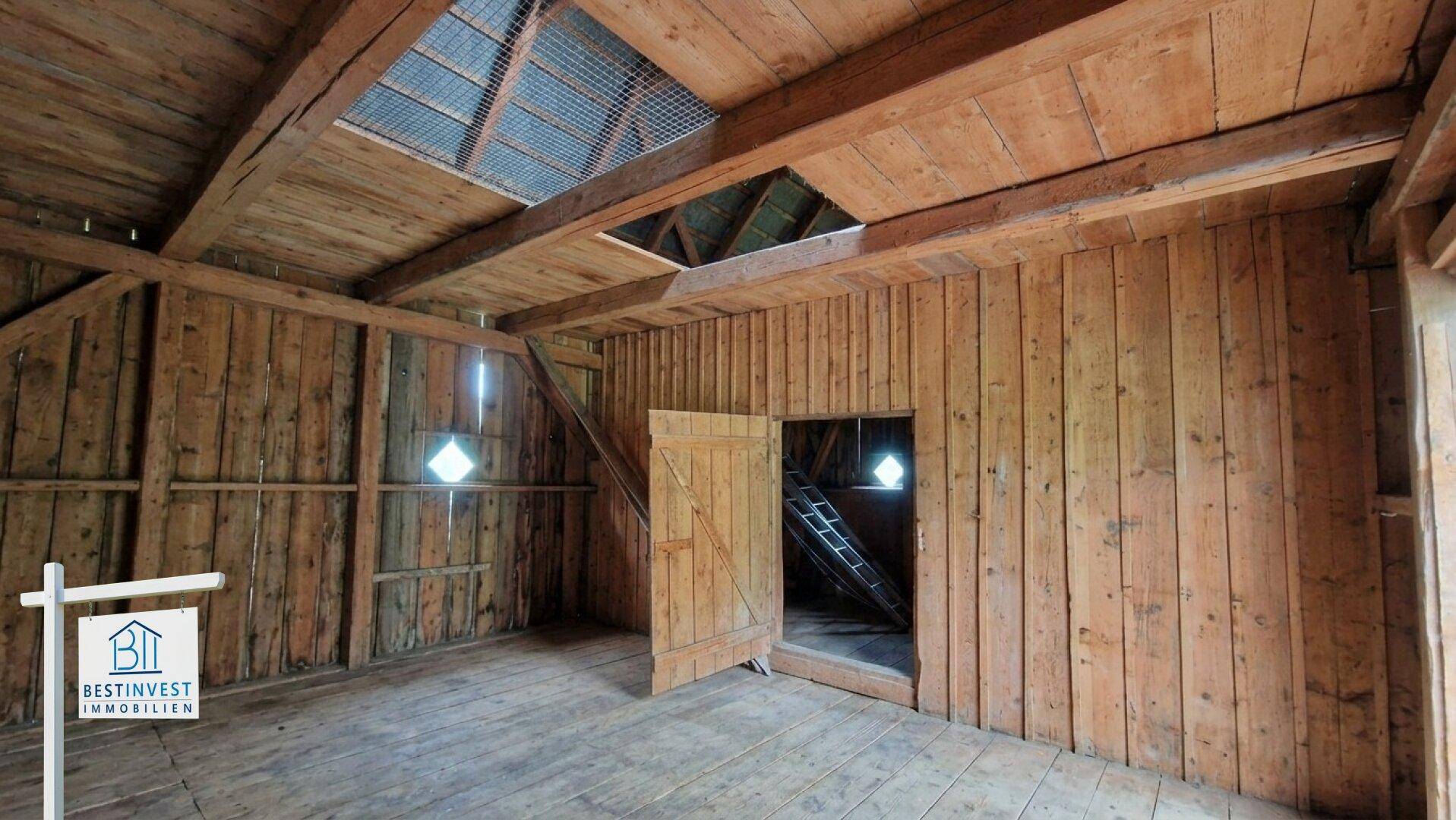Geräumiger Innenraum der Scheune mit Holzbalken und natürlicher Belichtung.