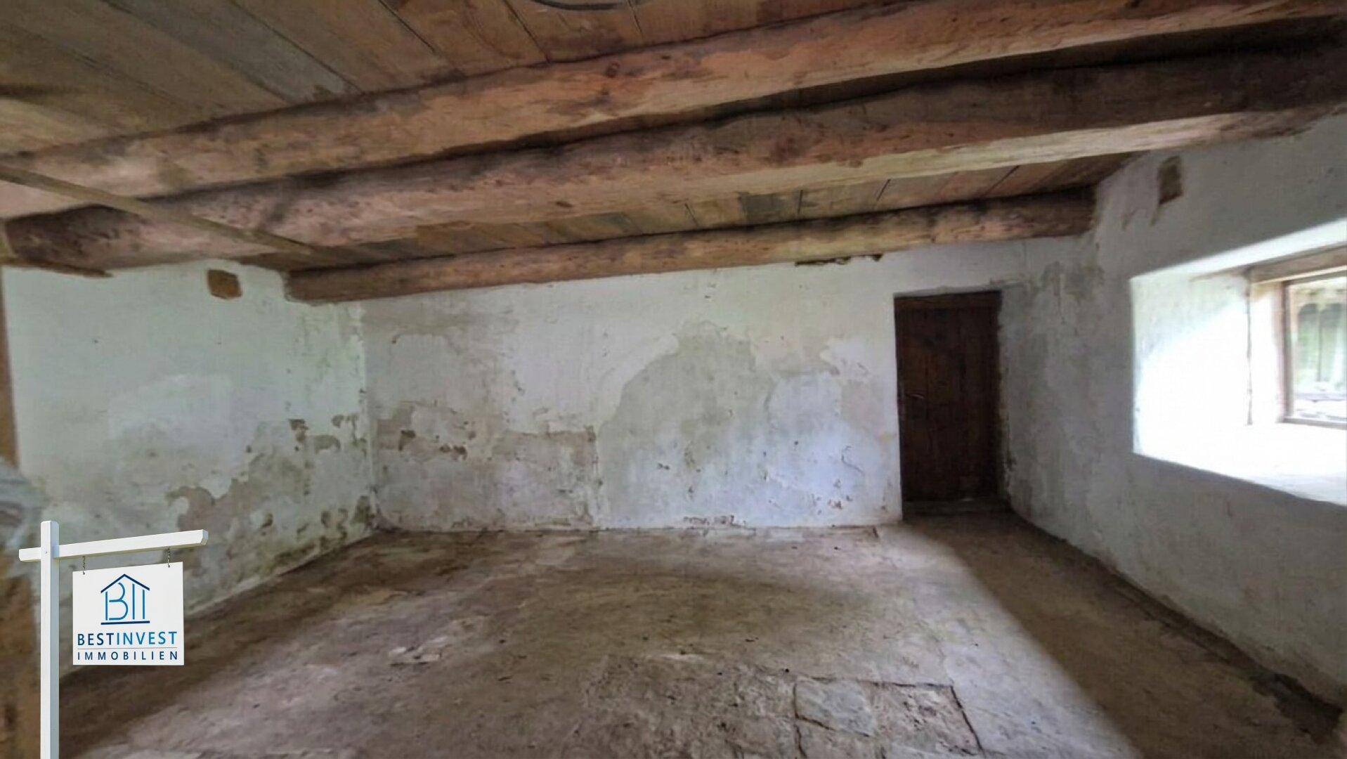 Unausgebauter Kellerraum mit rauen Wänden und Holzbalkendecke, ideal als Lager.