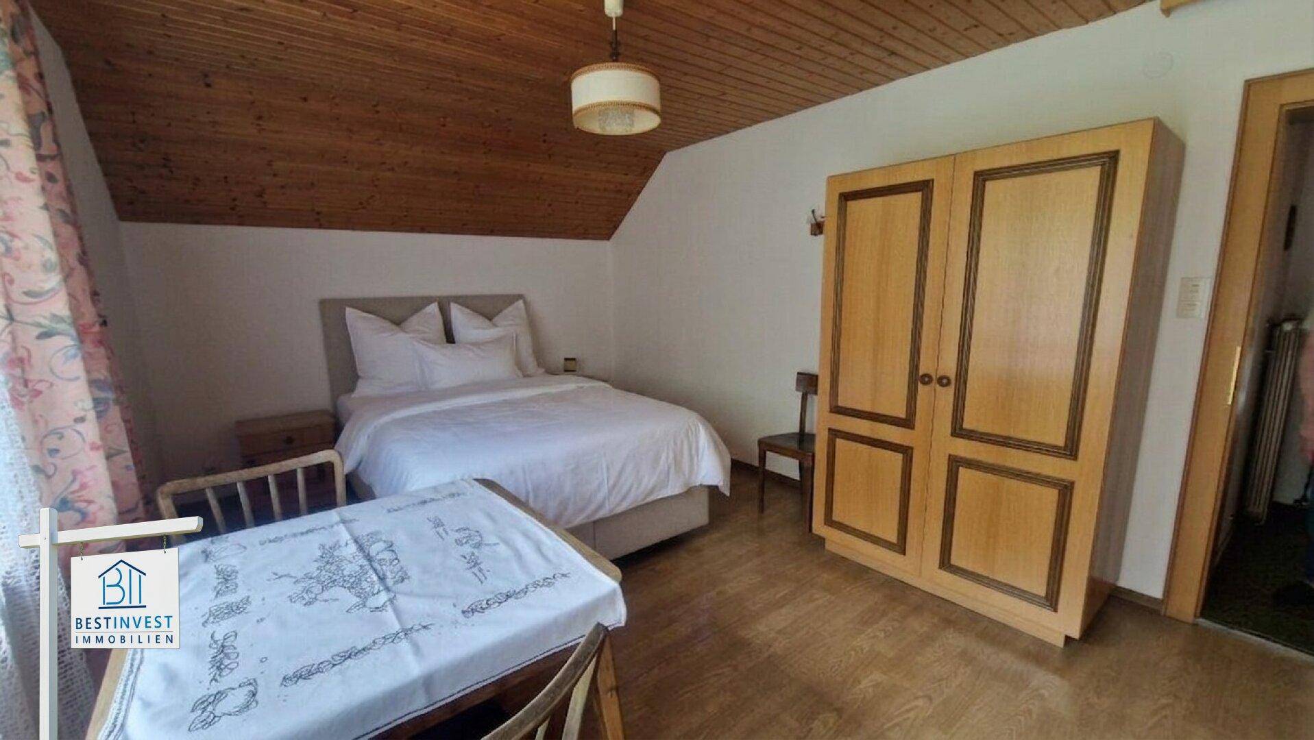Gemütliches Schlafzimmer mit Holzbalkendecke, Doppelbett und traditionellem Kleiderschrank.