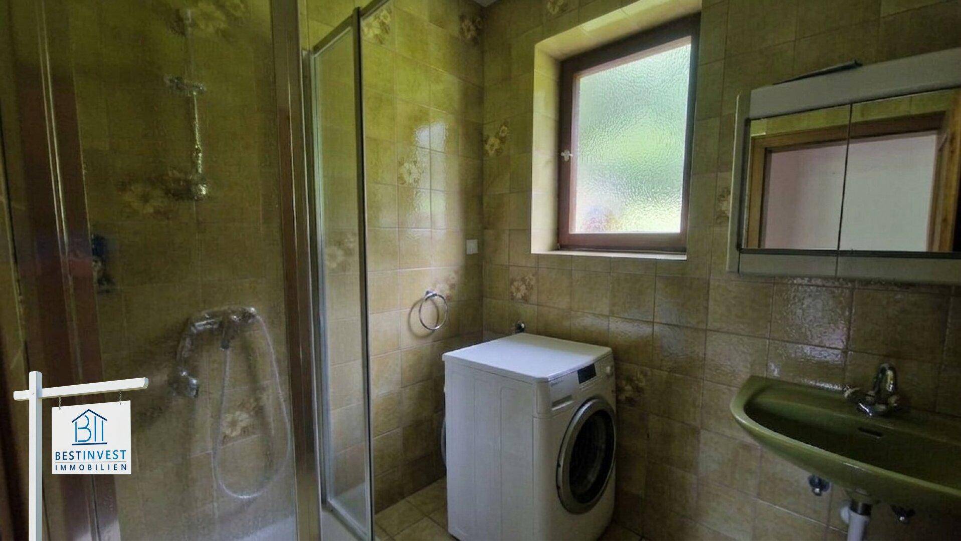 Badezimmer mit Dusche, Waschmaschine und grün gefliesten Wänden im Landhausstil.