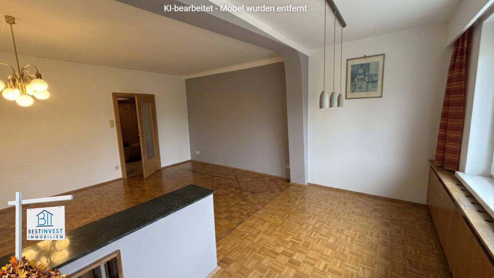 Leerer Wohn- und Essbereich mit Parkettboden und einem Durchgang zu weiteren Räumen.