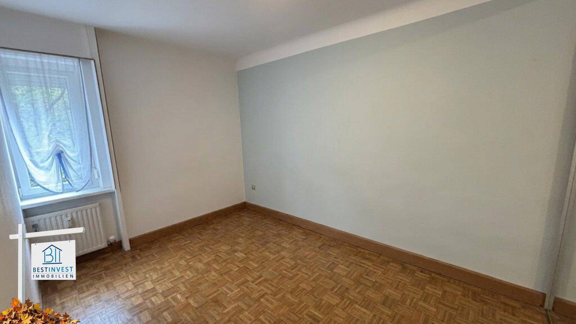 Leeres Schlafzimmer mit Parkettboden und einem Fenster, bereit zur individuellen Einrichtung.