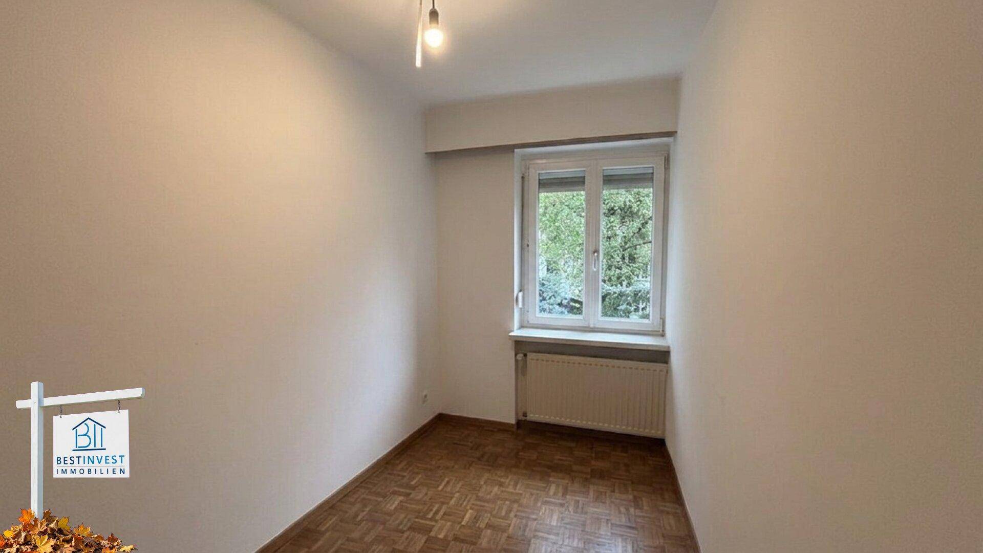 Kleines, leeres Zimmer mit Parkettboden und Fenster, ideal als Kinder- oder Arbeitszimmer.