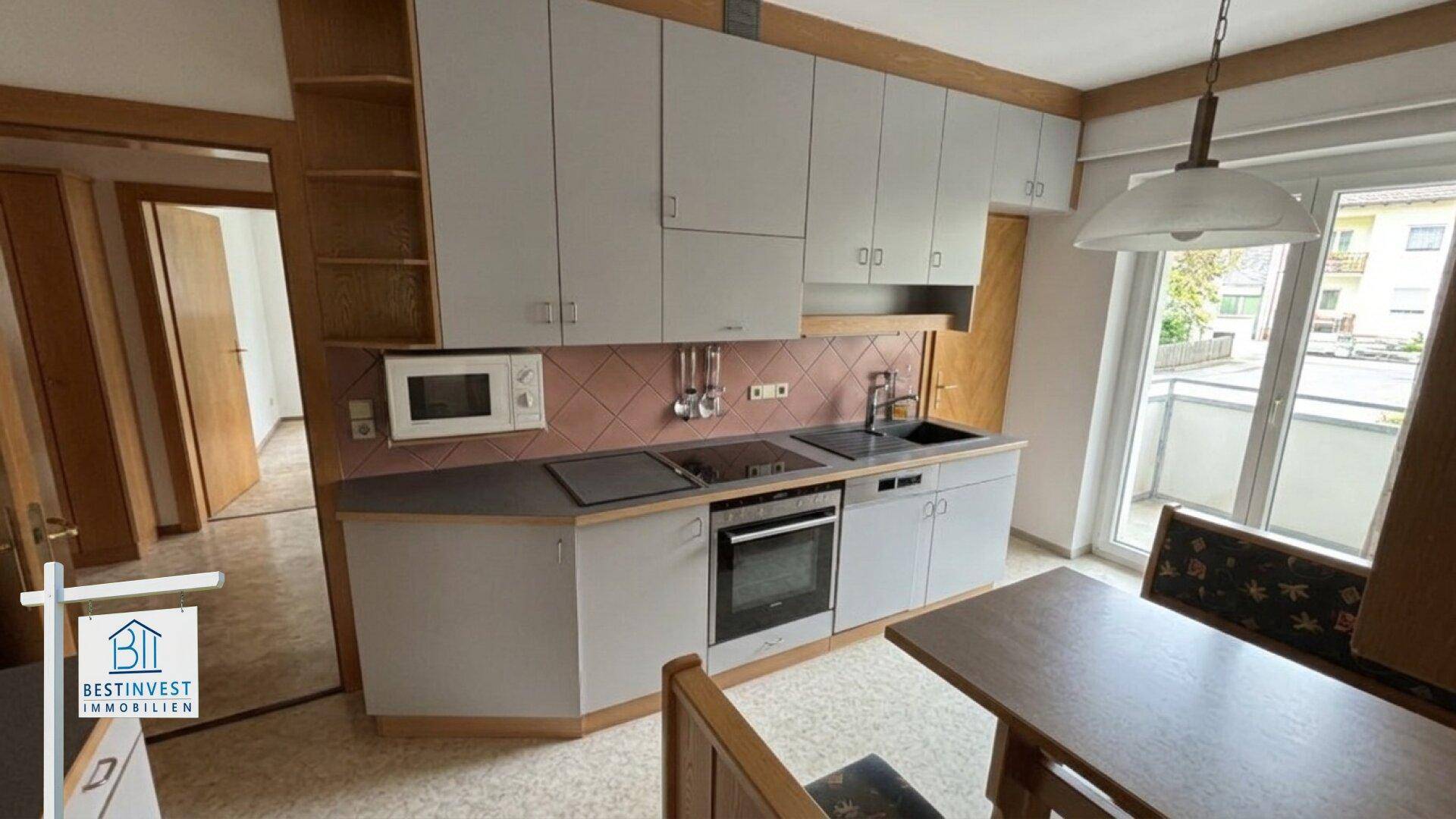 Funktionale Küche mit Einbauschränken, Geräten und direktem Zugang zum Balkon.