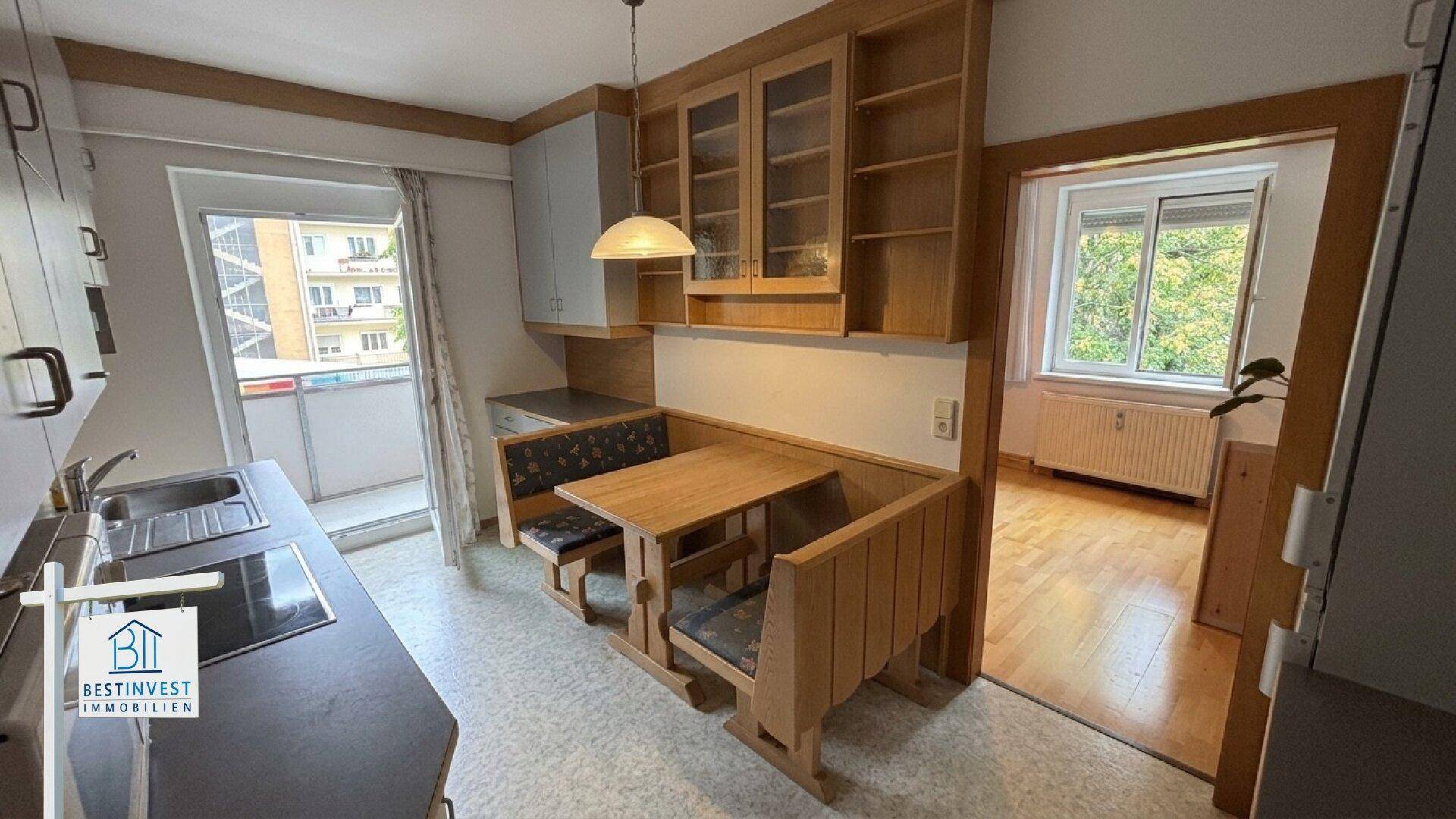 Gemütliche Küche mit Essecke, Holzschränken und Zugang zum sonnigen Balkon.