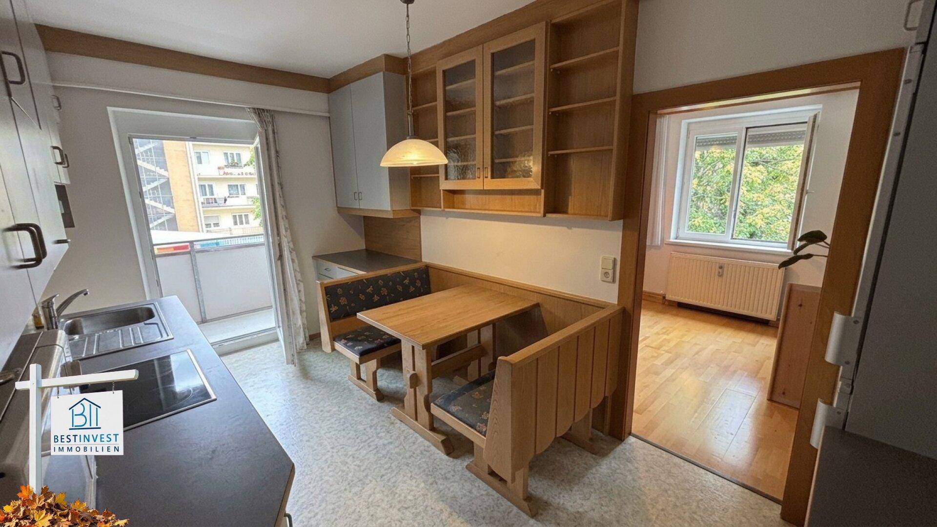 Helle Küche mit Essbereich, Holzmöbeln und direktem Zugang zum Balkon.