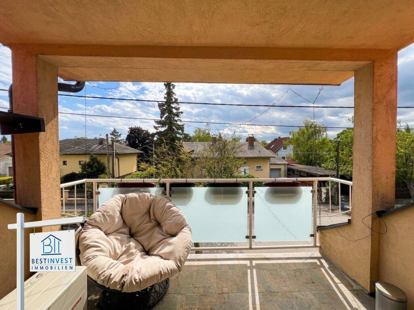 Überdachter Balkon mit bequemen Sitzgelegenheiten und Blick auf die Umgebung.