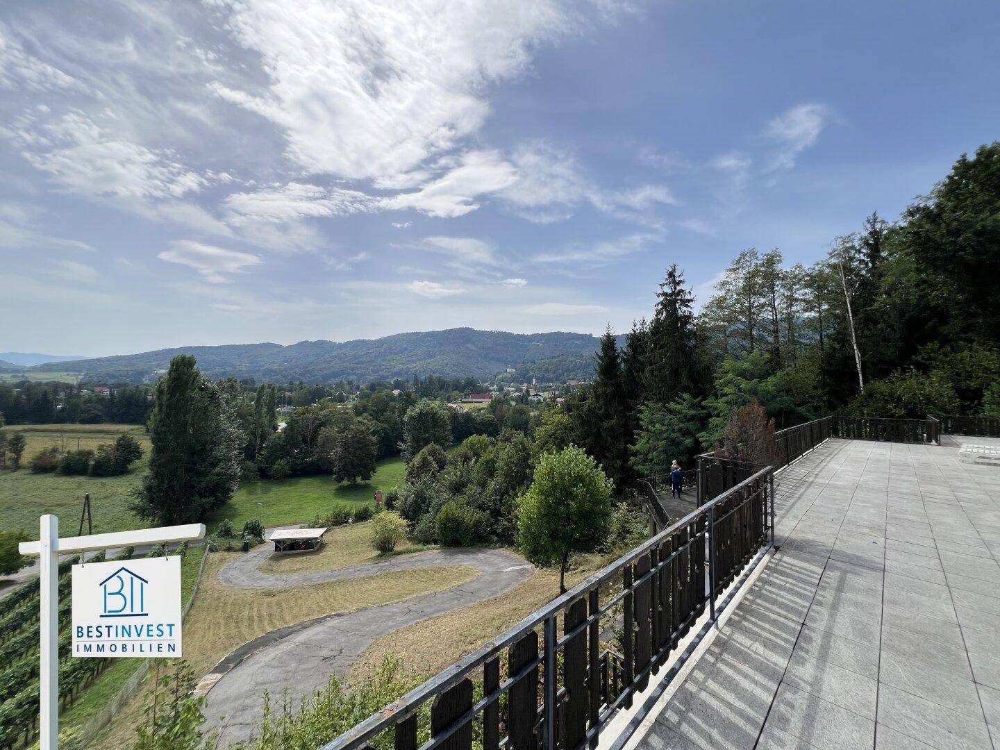 Weitläufige Terrasse mit Geländer und Panoramablick über das Tal und die grüne Landschaft.