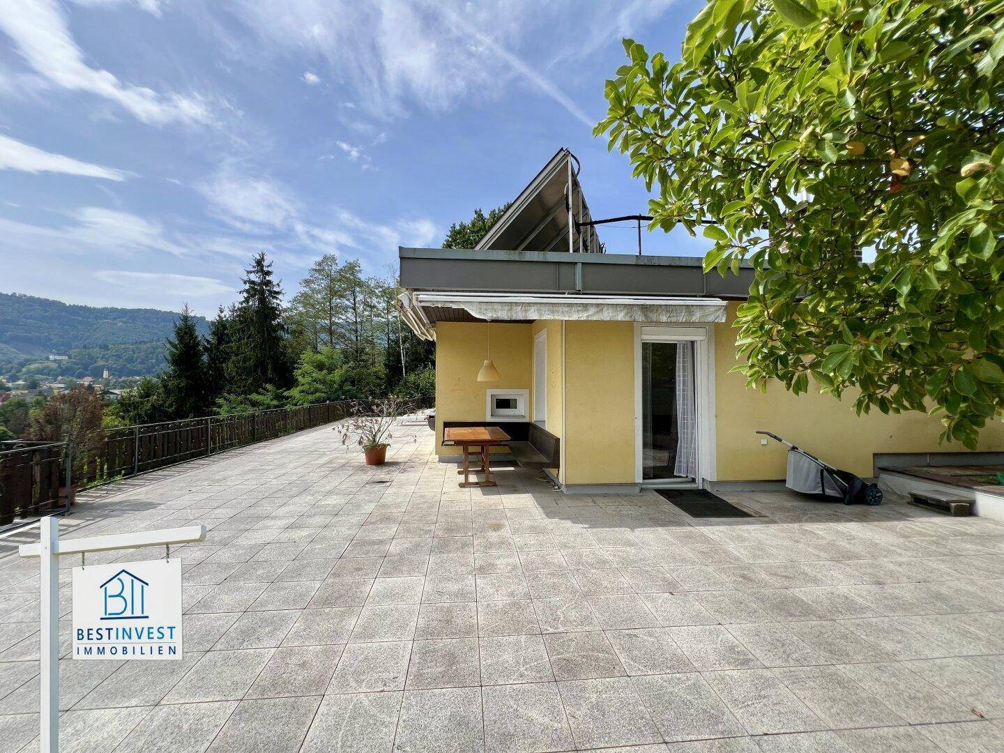 Weitläufige geflieste Terrasse mit Tisch und Stühlen, ideal für entspannte Stunden im Freien.