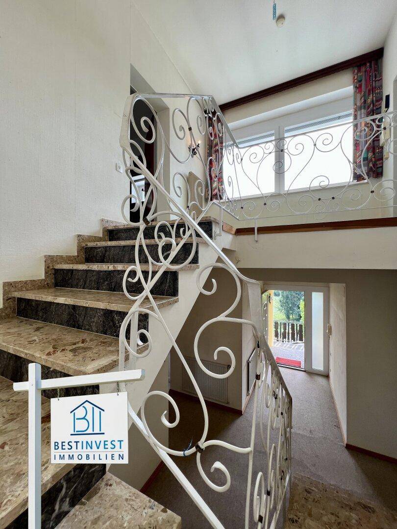 Elegante Treppe mit Marmorstufen und kunstvollem schmiedeeisernem Geländer, führt in den oberen Bereich.