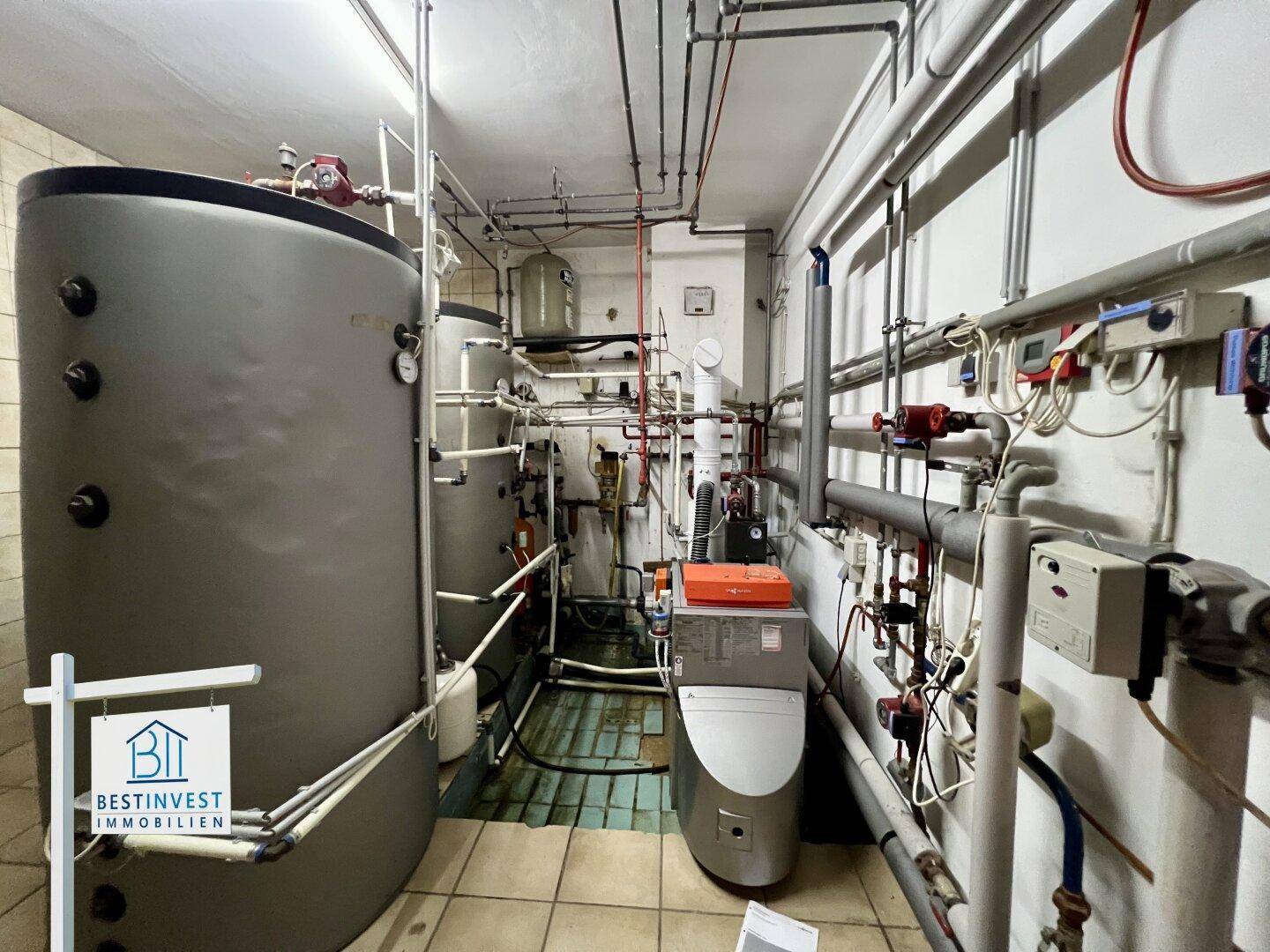 Heizungsraum im Keller mit großen Warmwasserspeichern und komplexer Rohrinstallation.