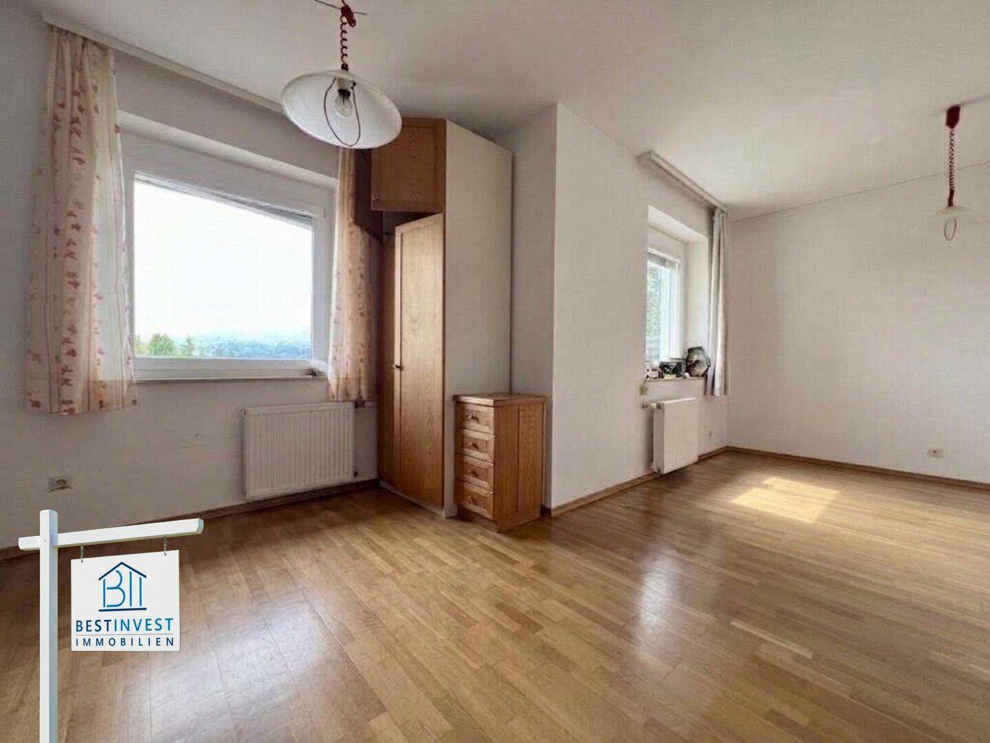 Geräumiges Zimmer mit Parkettboden, Einbauschrank und zwei Fenstern für viel Licht.