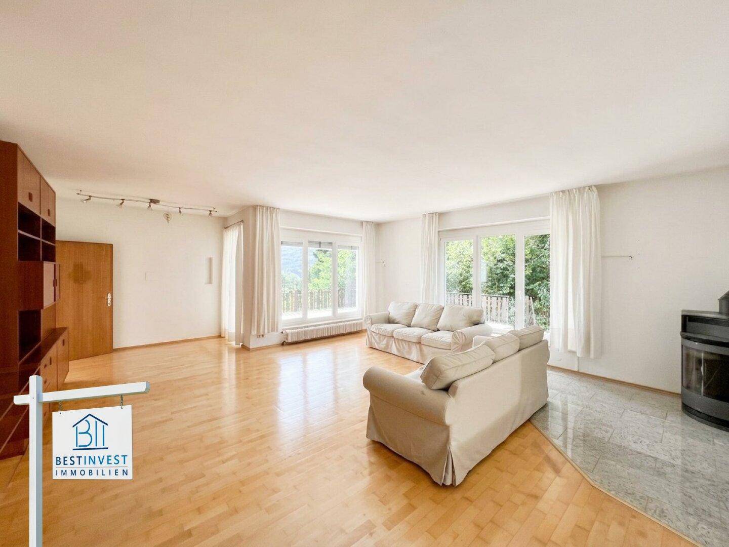 Helles Wohnzimmer mit Parkettboden, zwei Sofas und einem Kaminofen.